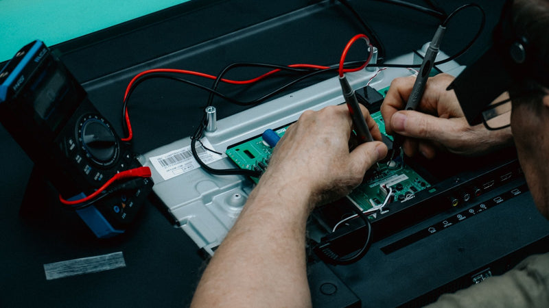 Technician testing a circuit board with a digital multimeter