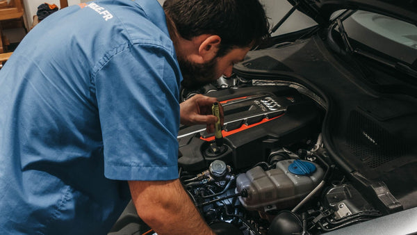 Mechanic checking a car engine under an open bonnet