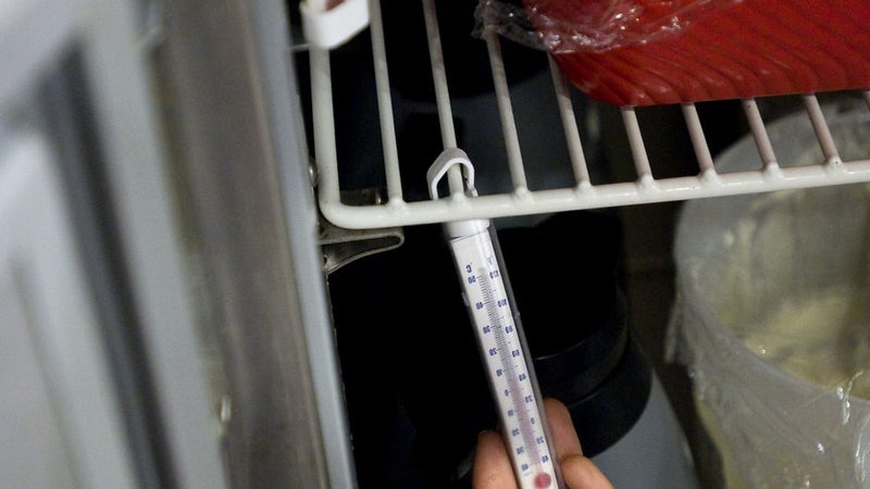 Checking a thermometer inside a stainless steel refrigerator
