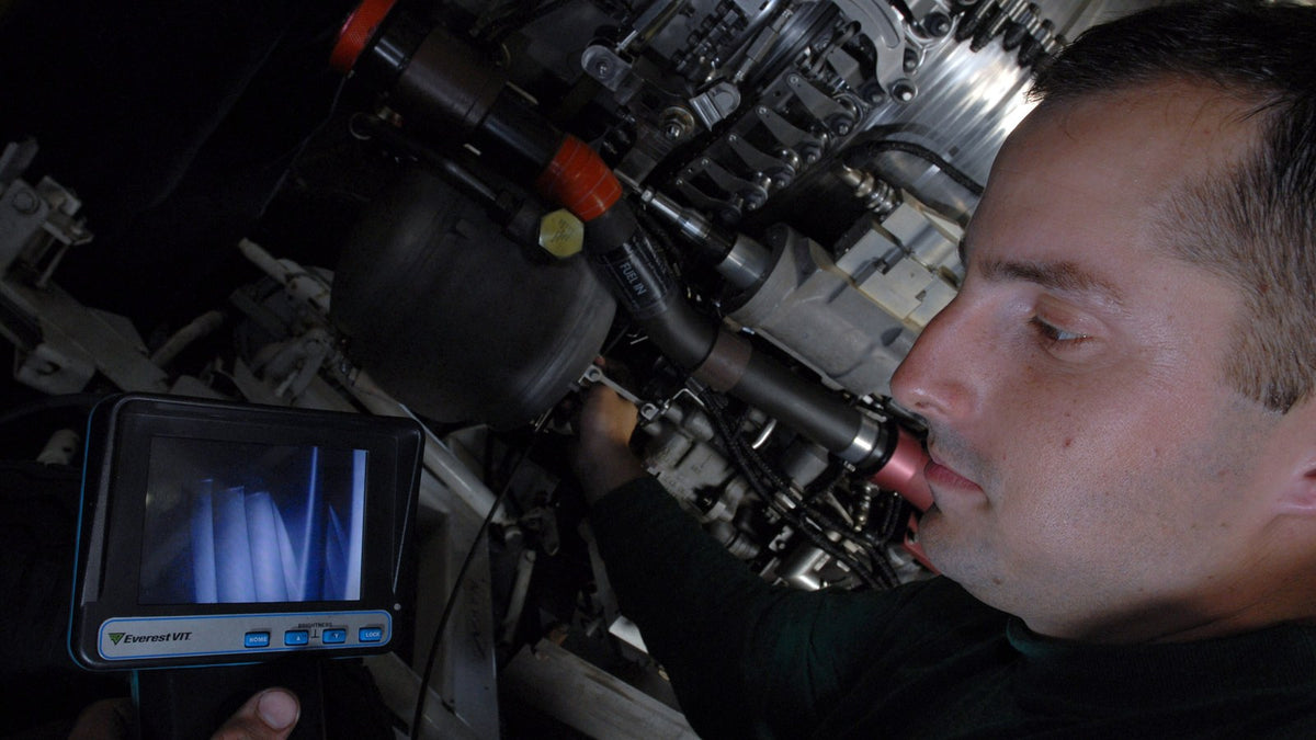 Technician inspecting an engine with a borescope and viewing screen