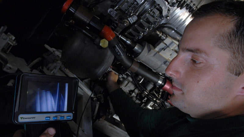Technician inspecting an engine with a borescope and viewing screen