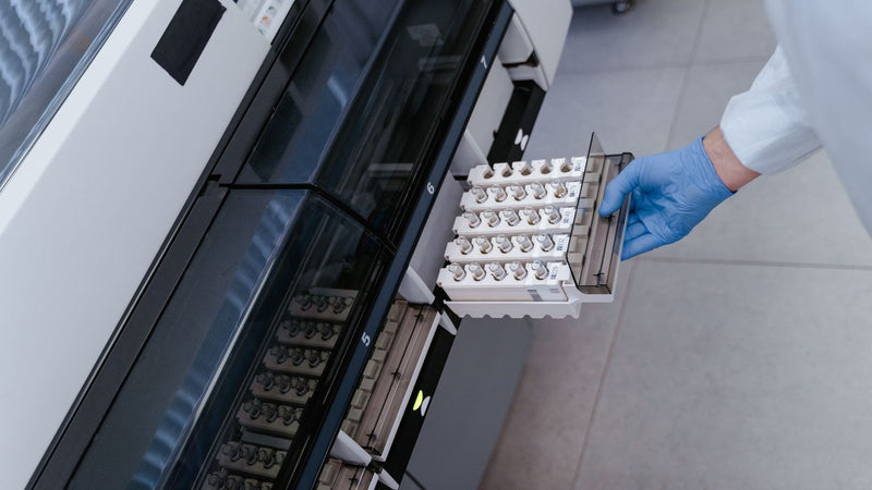Scientist loading sample tubes into a laboratory analyser