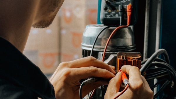Electrician testing wiring in an industrial cabinet with a handheld meter