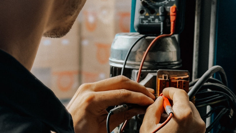 Electrician testing wiring in an industrial cabinet with a handheld meter